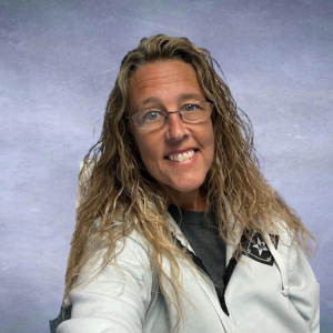 Breann Headshot of a woman with blonde curly hair and glasses