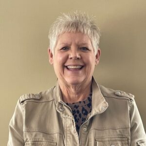 Wendy Headshot of a woman with brown hair pulled back wearing a green sweater